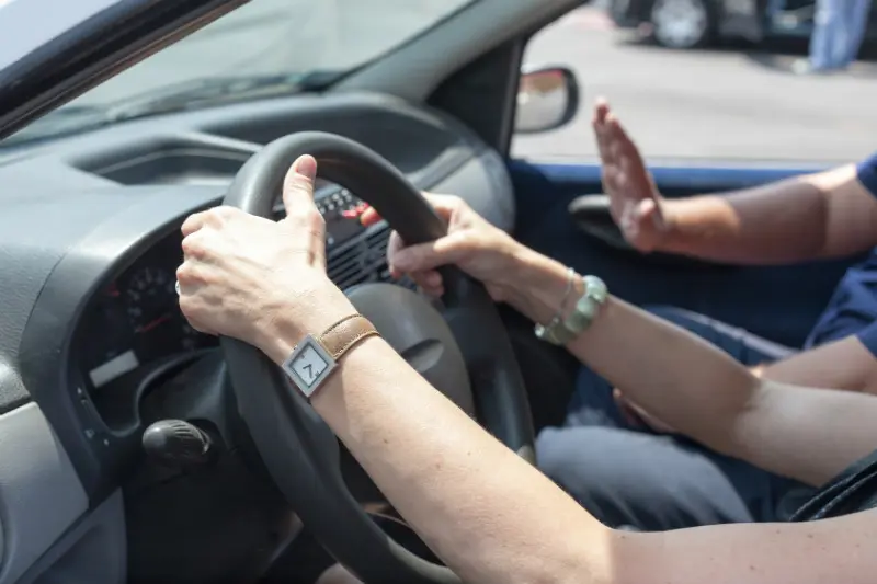 A student driver's hands holding the steering wheel.