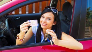 Woman inside a red car holding car keys and driver’s license