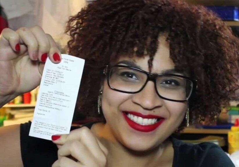 A woman holding up a receipt with a smile on her face.